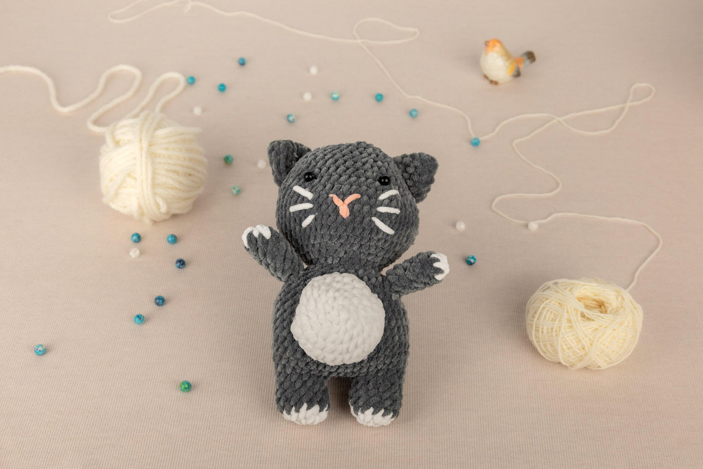 a crocheted cat next to a ball of yarn
