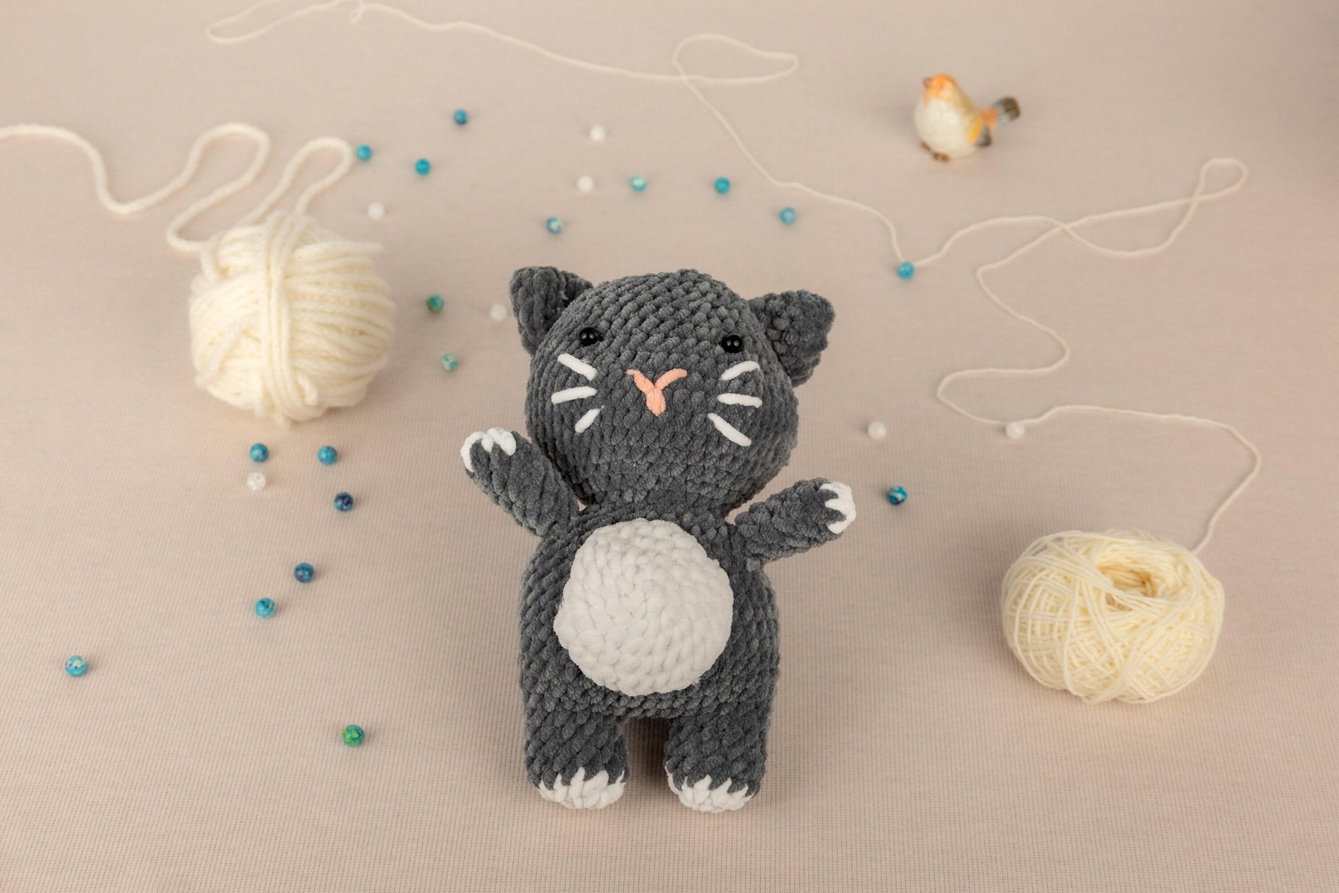 a crocheted cat next to a ball of yarn