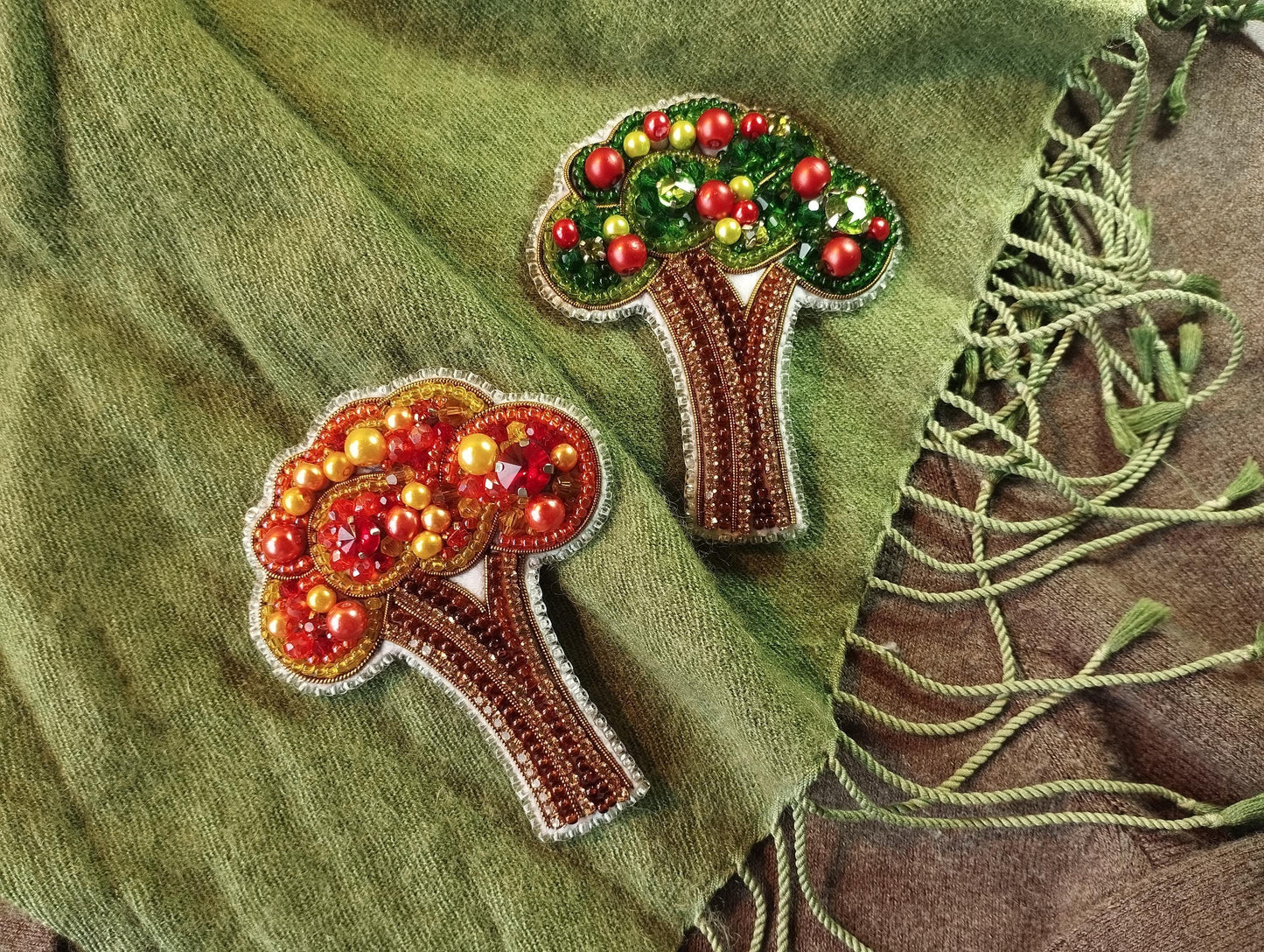 a close up of two embroidered trees on a green cloth