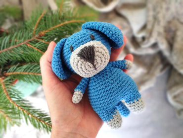 a hand holding a small crocheted stuffed animal