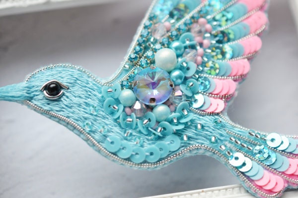 a blue bird with beads and jewels on it&#39;s wings