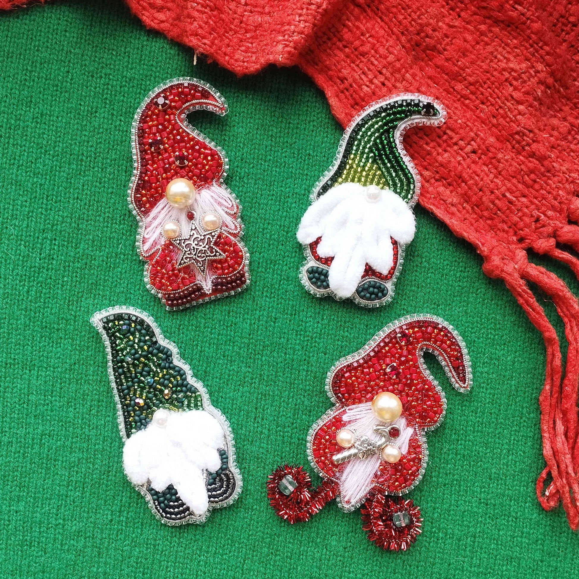 four decorative Christmas ornaments, each with a unique design and color scheme, arranged on a green background.