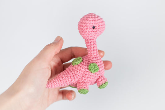 a hand holding a pink crocheted toy that looks like a giraffe