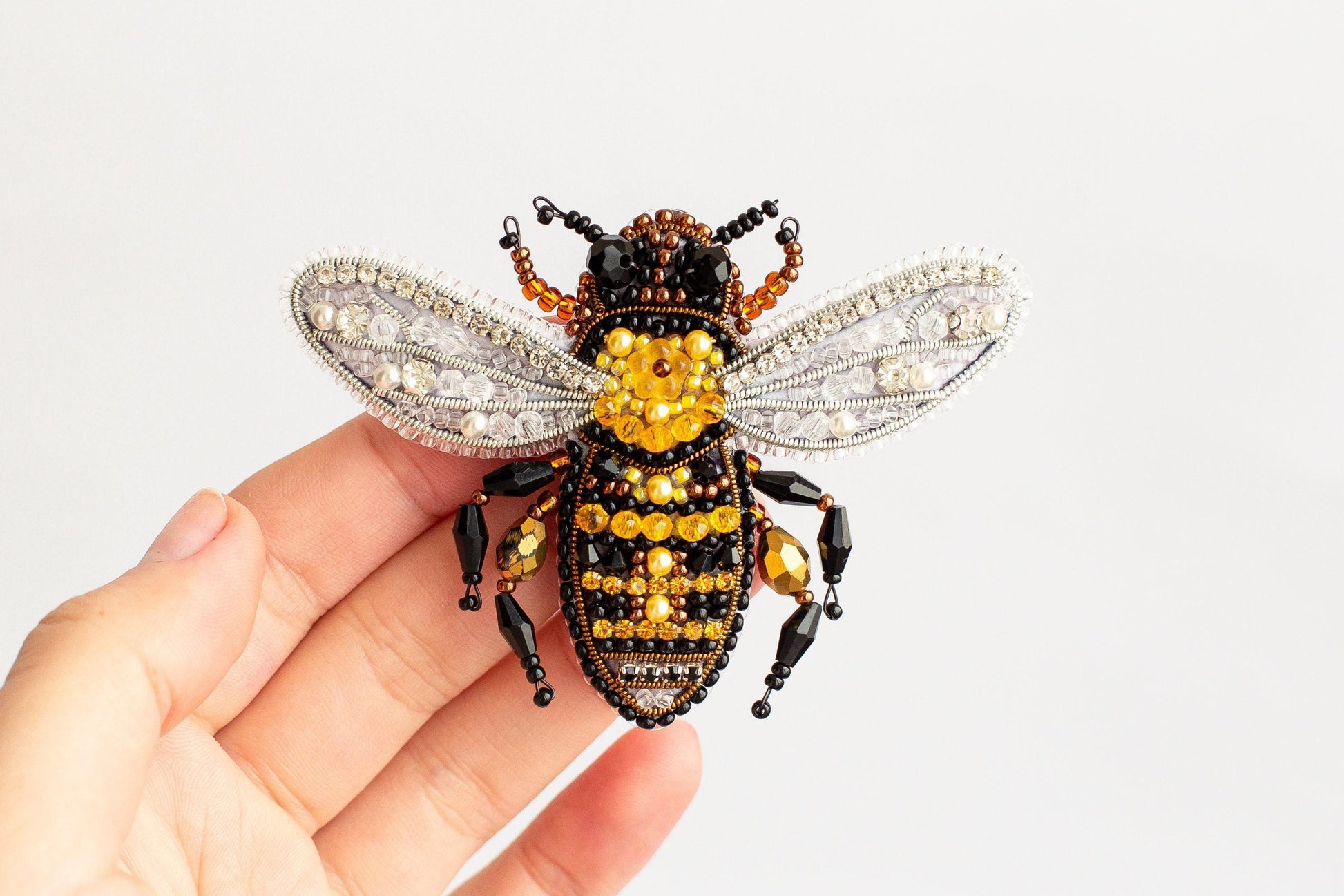 a hand holding a tiny beaded bee