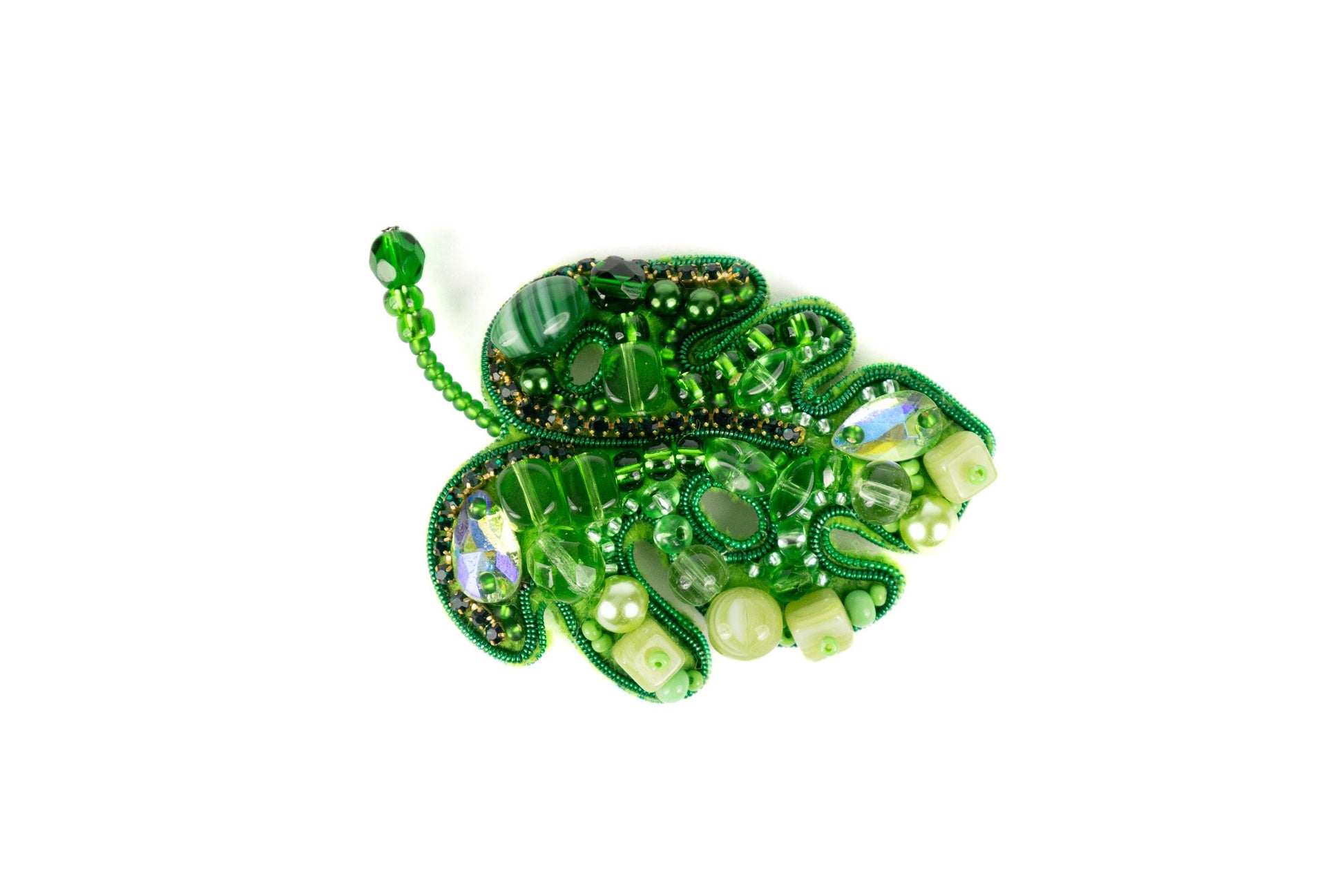 a green brooch with pearls and beads
