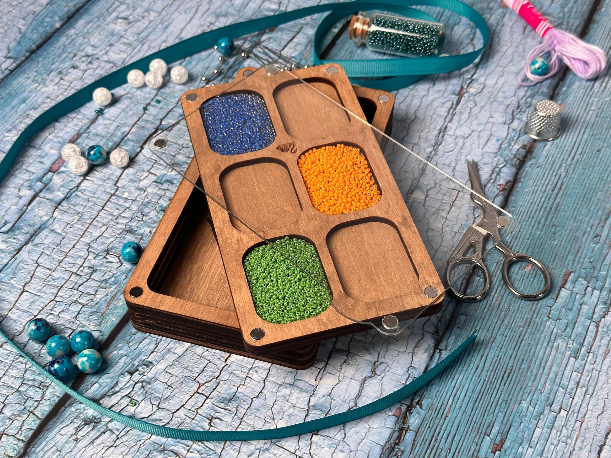a wooden box filled with beads and a pair of scissors