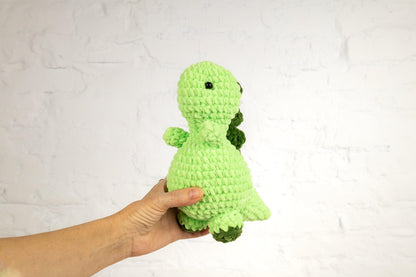 a hand holding a green crocheted stuffed animal