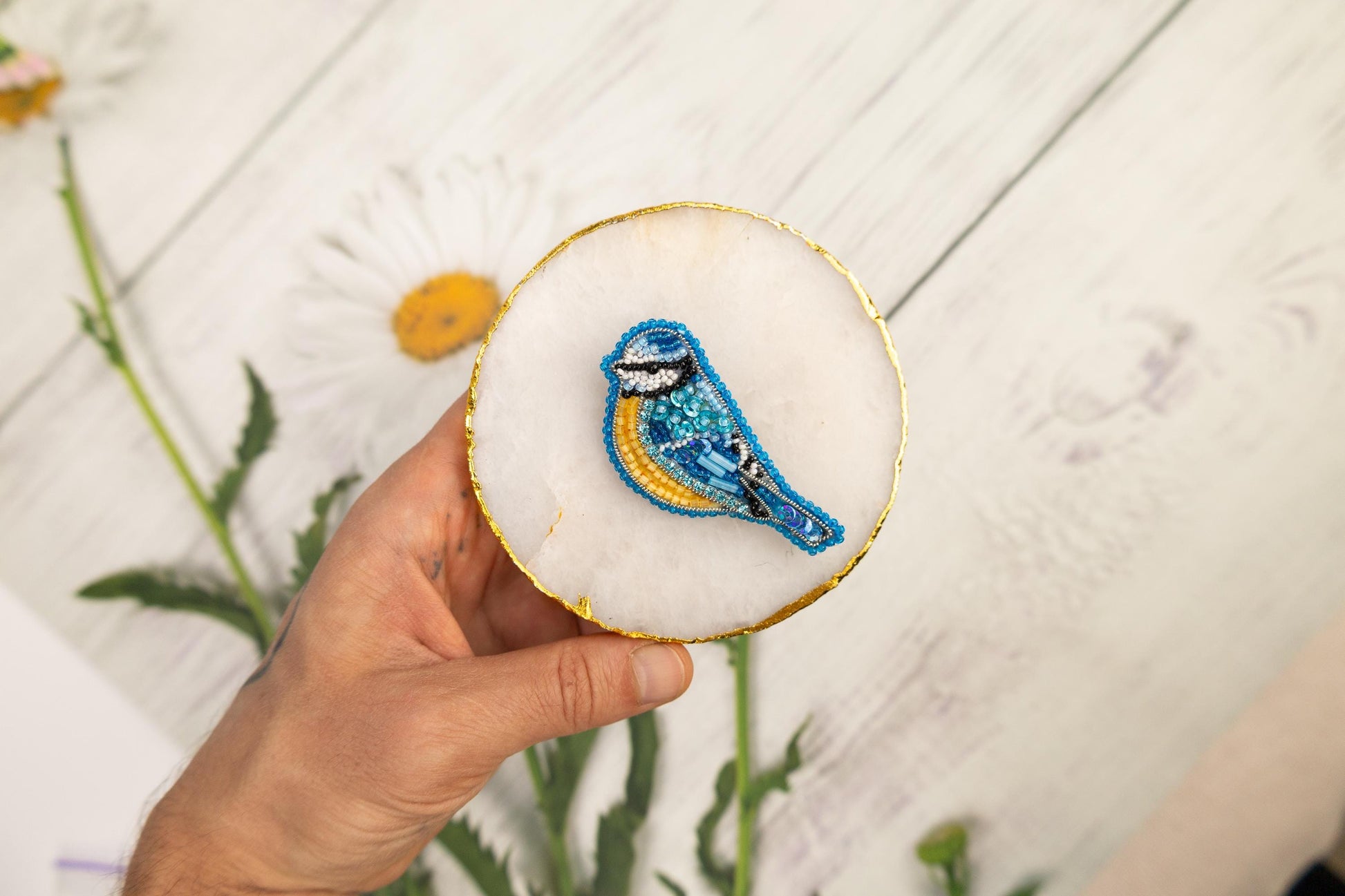 a hand holding a small blue bird on a white plate