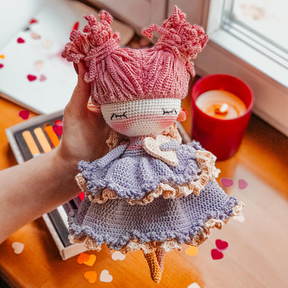 a hand holding a knitted doll on a table