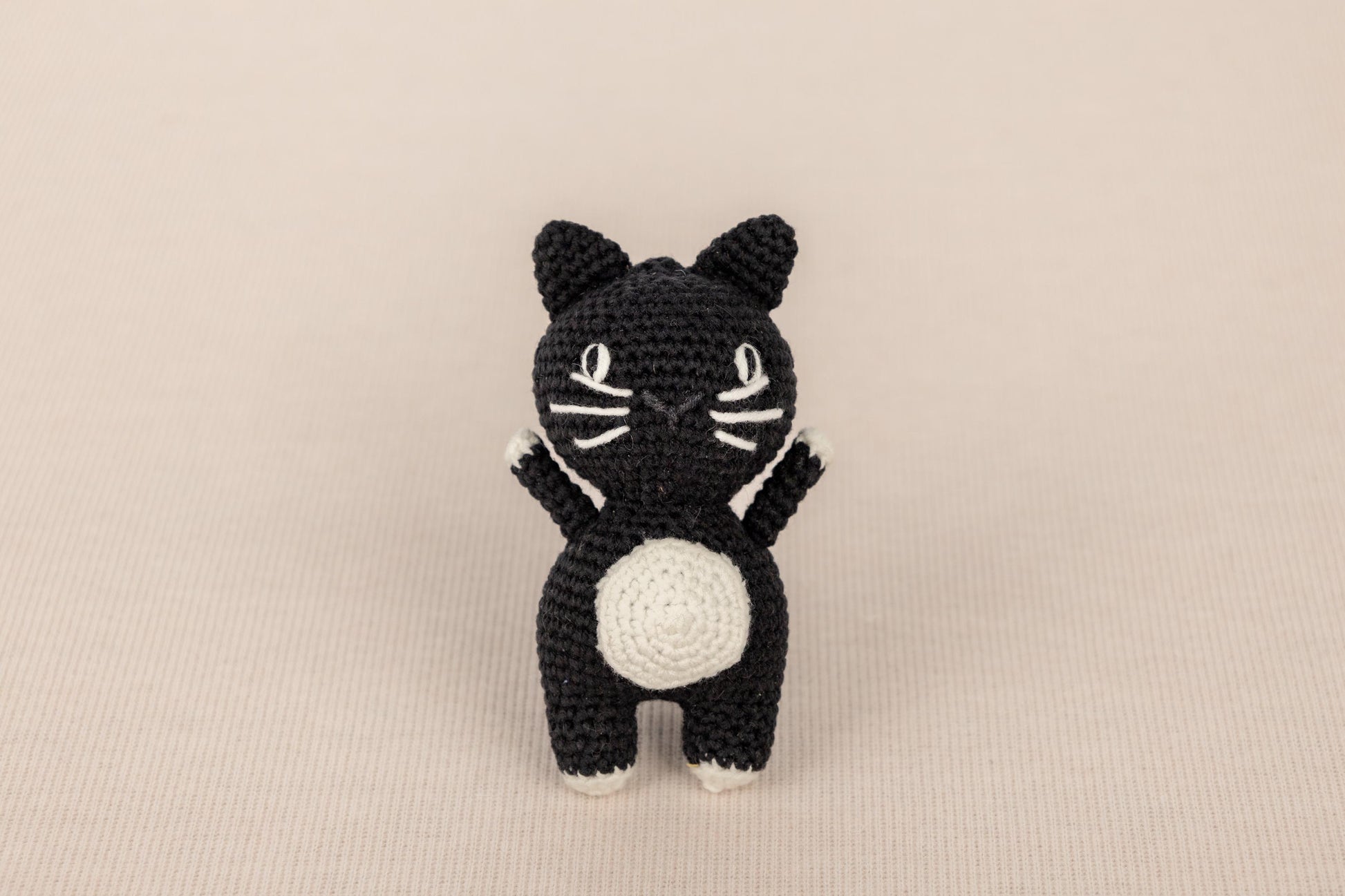 a crocheted black and white cat sitting on its hind legs