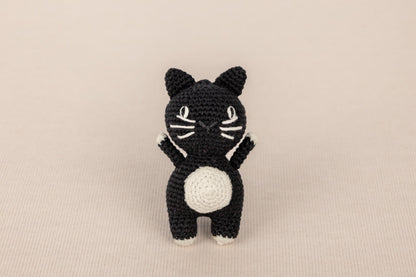 a crocheted black and white cat sitting on its hind legs