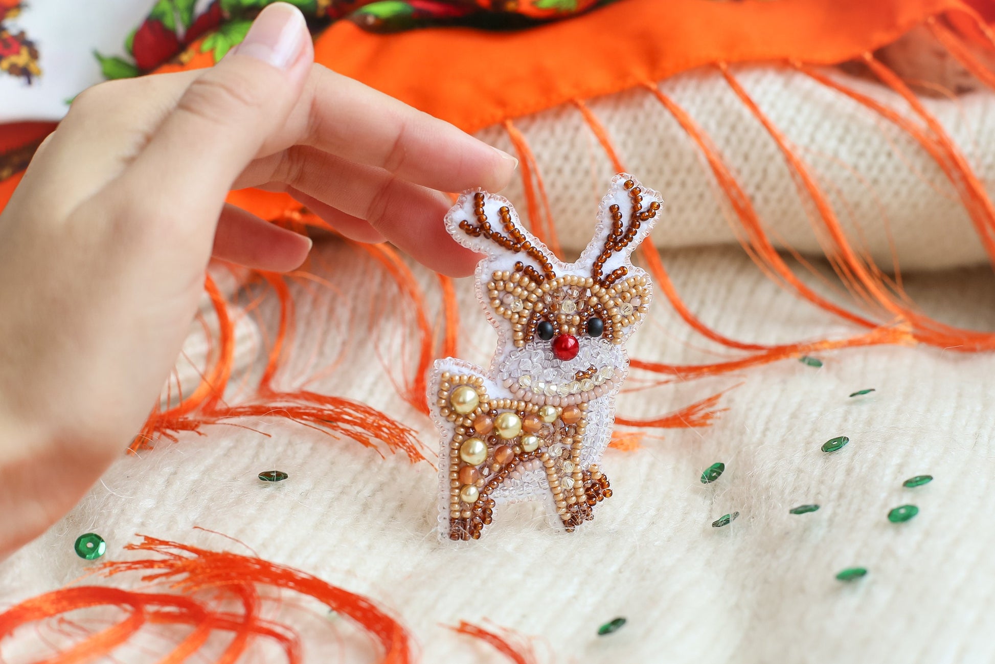 a hand is holding a beaded deer ornament