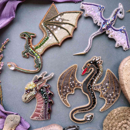 a collection of intricately designed dragon-shaped embellishments, including a dragon with a green body, a purple dragon, and a black dragon, all adorned with sparkling jewels and beads.