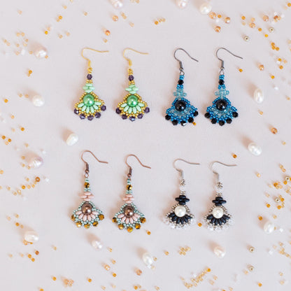 a collection of earrings with various colors and designs, including green, blue, black, and pink, arranged on a light background with scattered pearls and beads.
