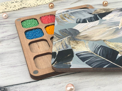 a wooden tray with paint and some beads