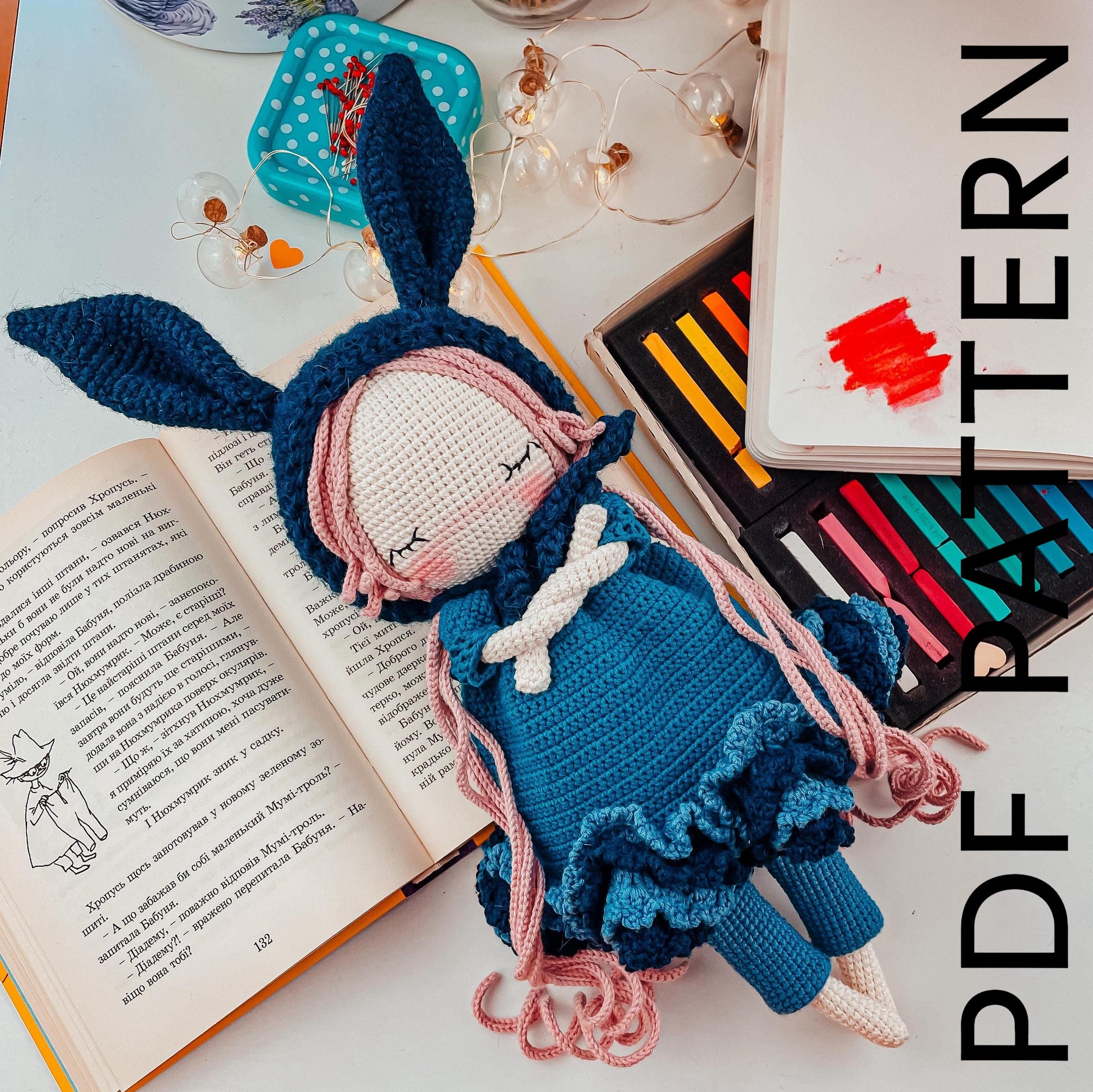 a crocheted doll sitting next to an open book