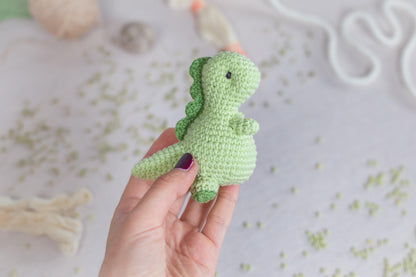 a hand holding a small green crocheted toy