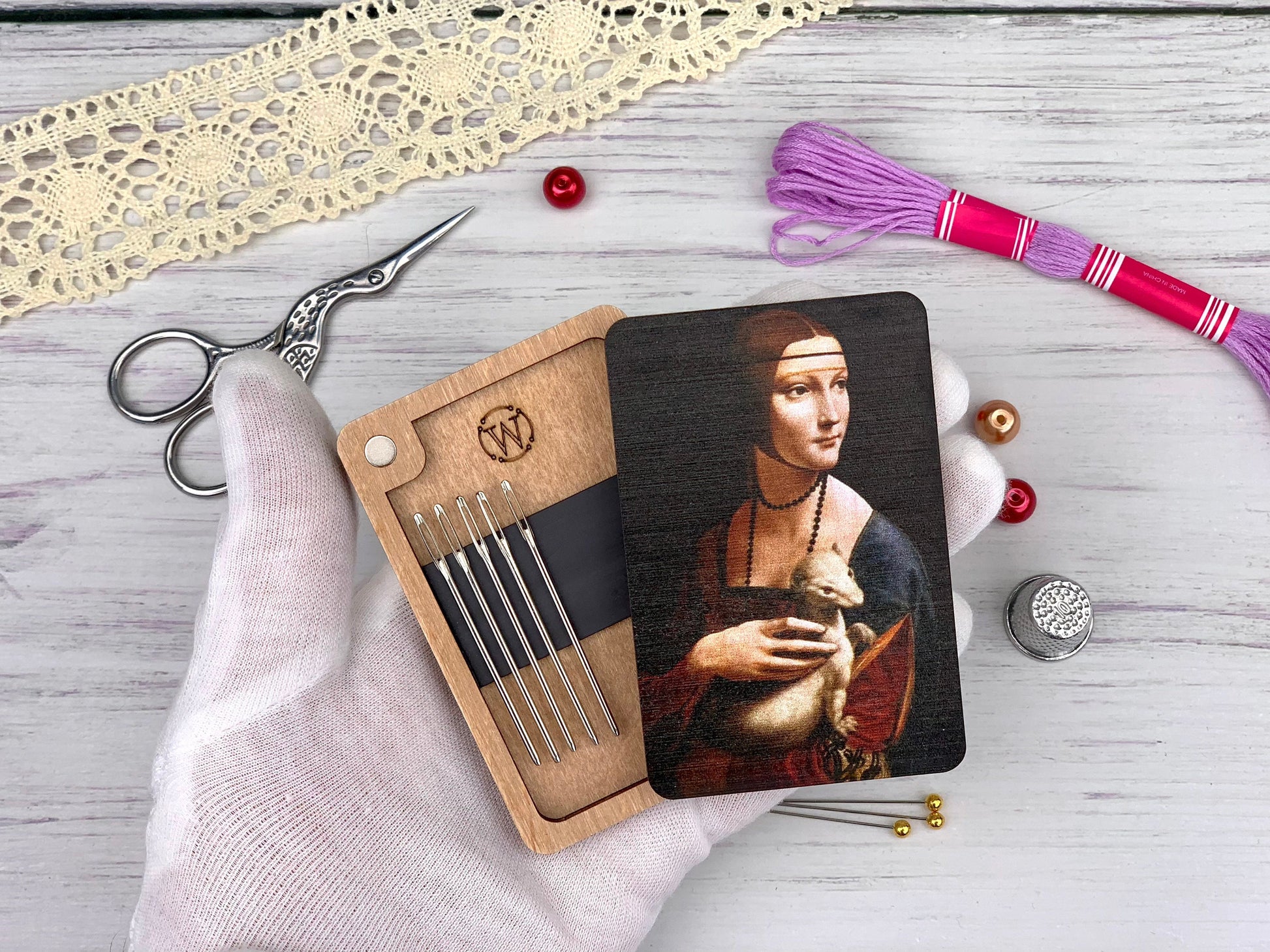 a hand holding a wooden coaster with a picture of a woman holding a cat