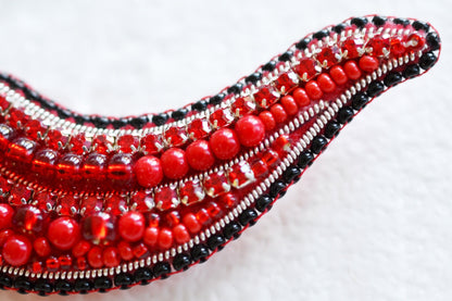 a close up of a red beaded brooch