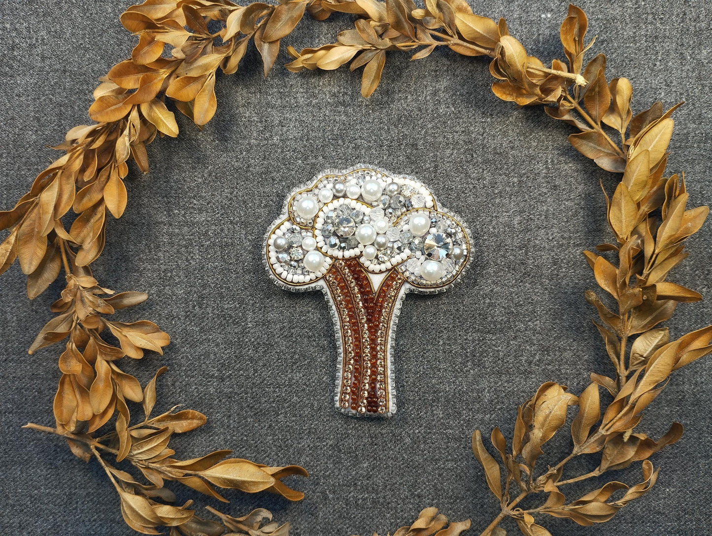 a brooch with a tree surrounded by leaves