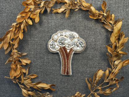 a brooch with a tree surrounded by leaves