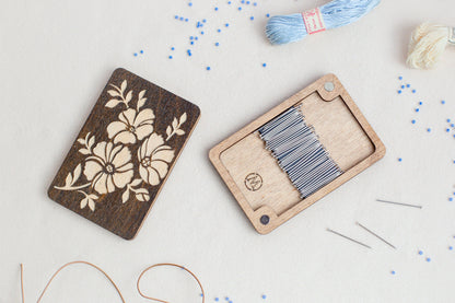 a wooden box with a needle and thread next to it