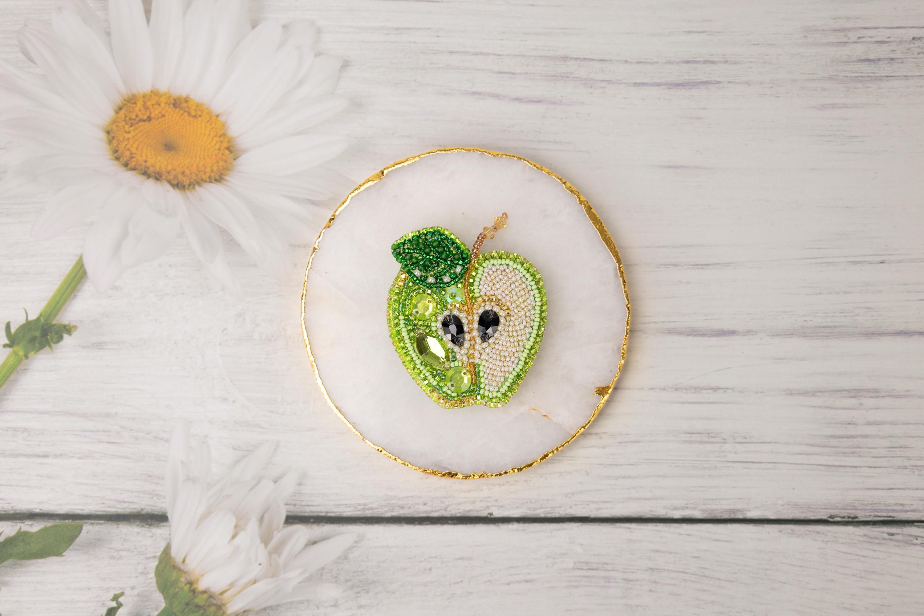 a green apple brooch sitting on top of a white table