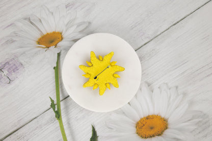 a white plate with a yellow flower on top of it