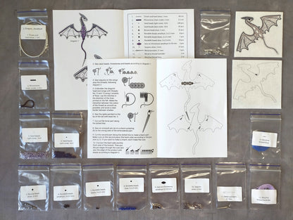 various sewing supplies and materials, including a diagram of a dragon, instructions, and several packages of beads and threads.