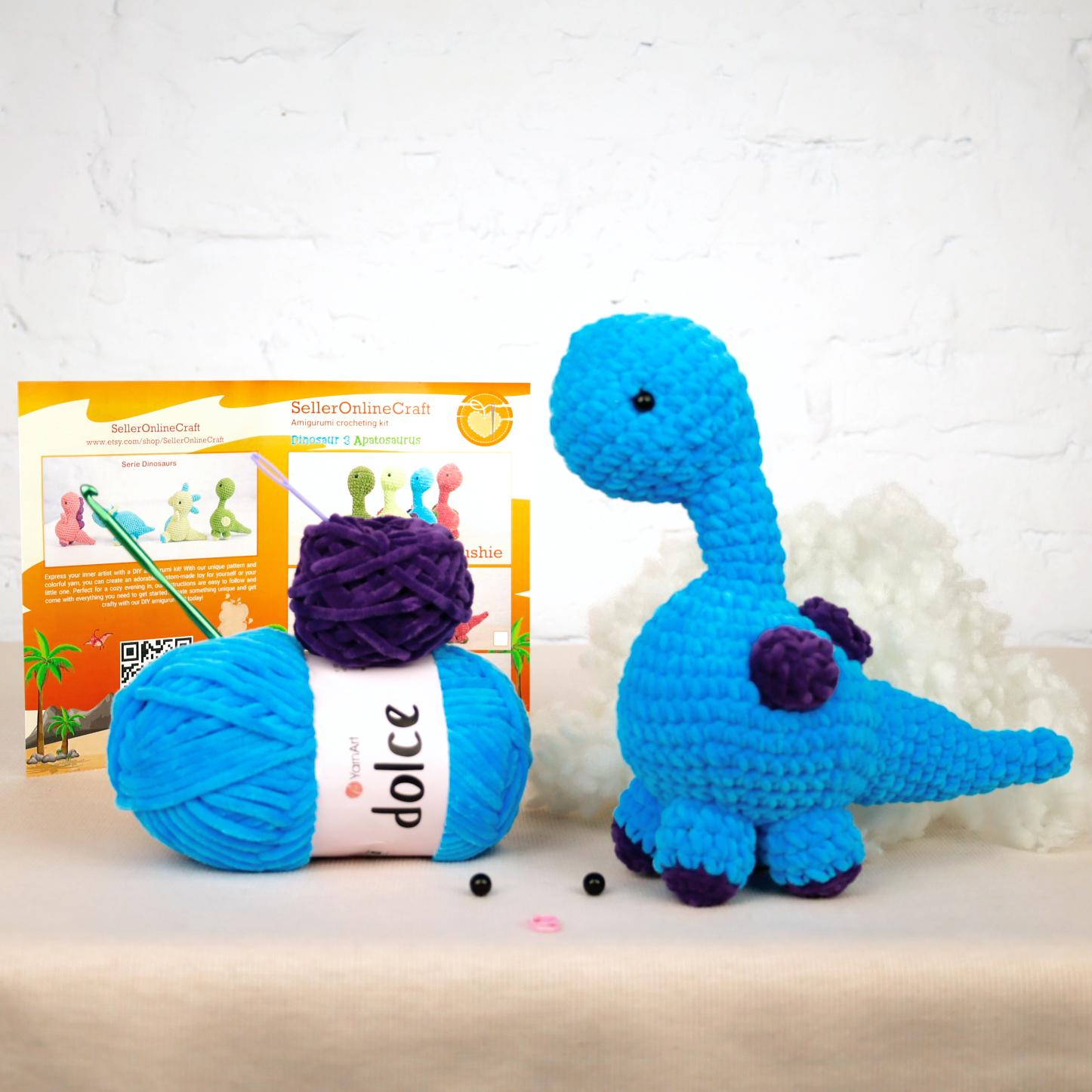a blue crocheted dinosaur next to a ball of yarn