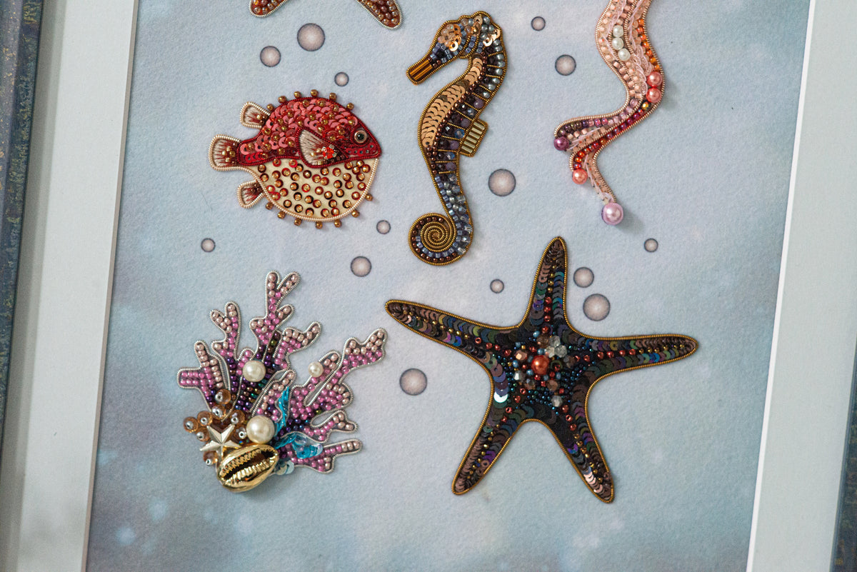 a collection of colorful, intricately designed sea creatures, including a red fish, a brown seahorse, a purple starfish, and a black starfish, all adorned with beaded and embroidered embellishments.