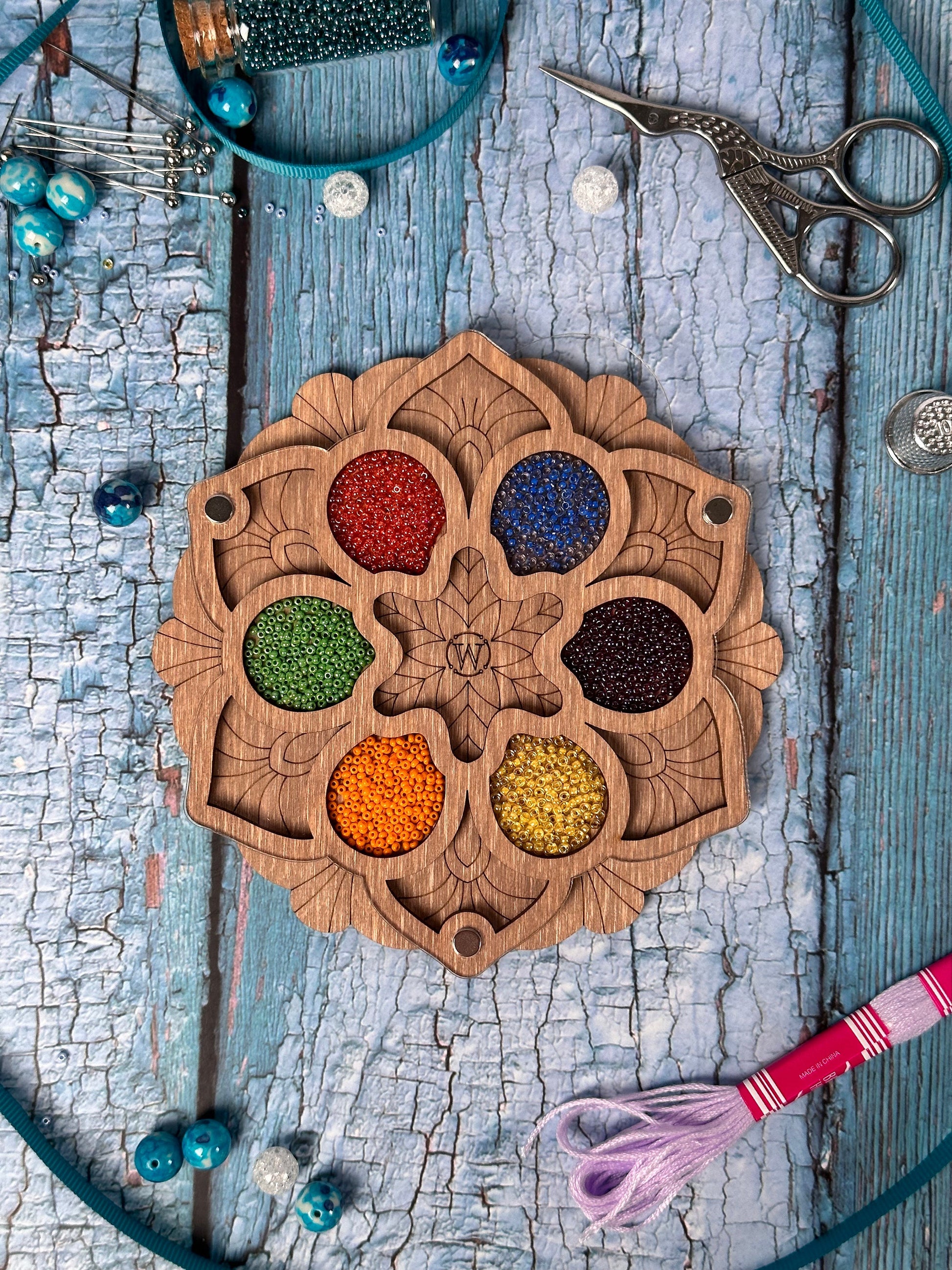 a wooden plate with a variety of beads and a pair of scissors