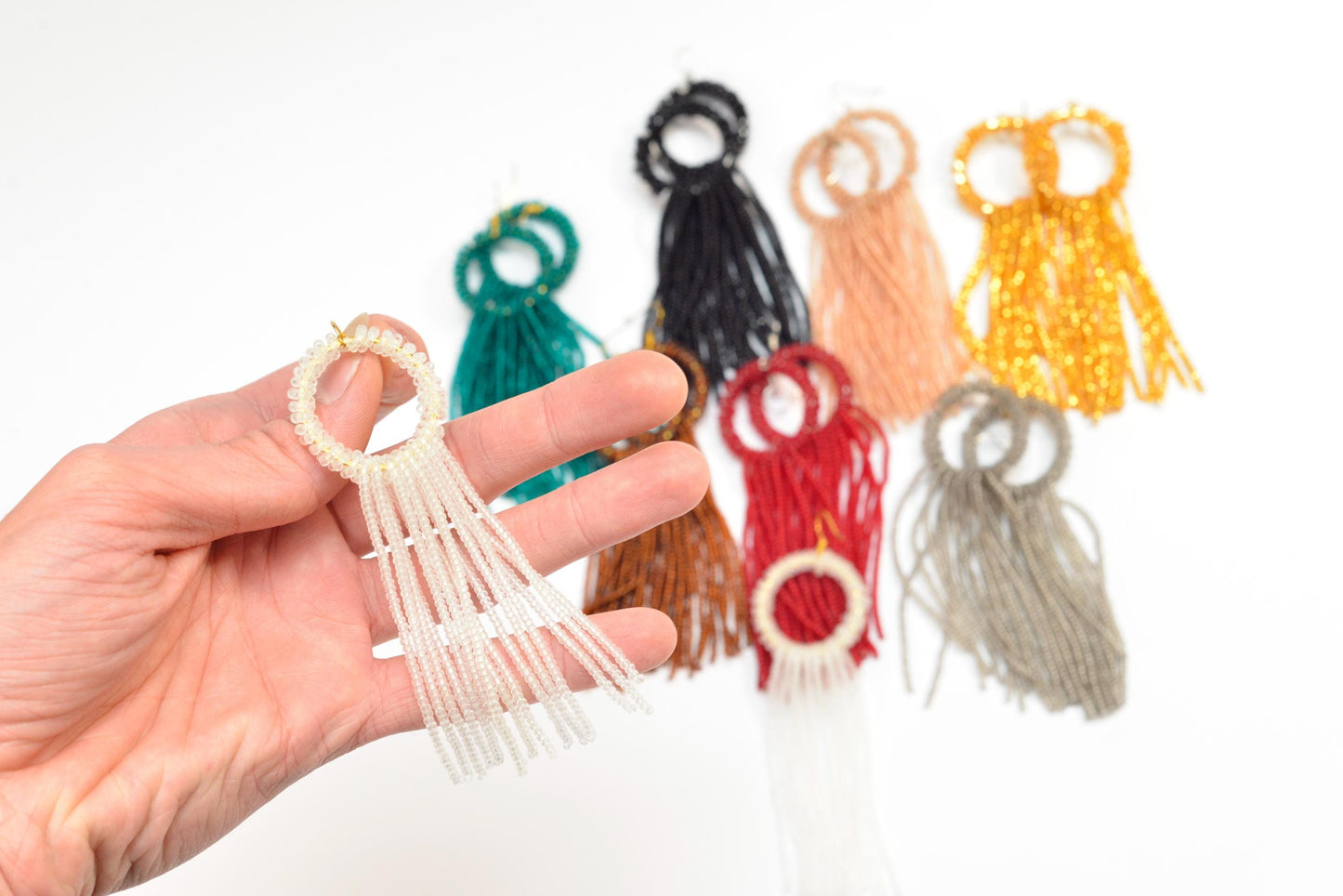 a hand holding a ring with tassels on it