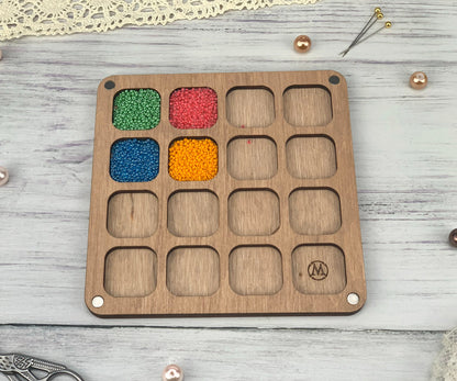 a wooden tray with beads in it on a table