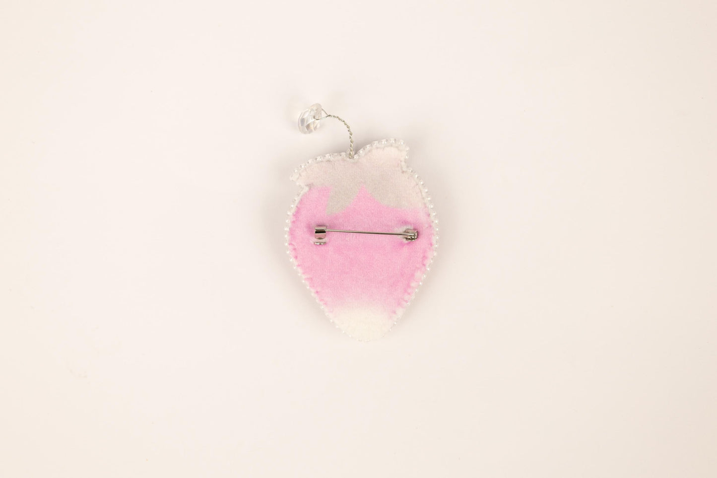 a pink and white brooch hanging from a hook