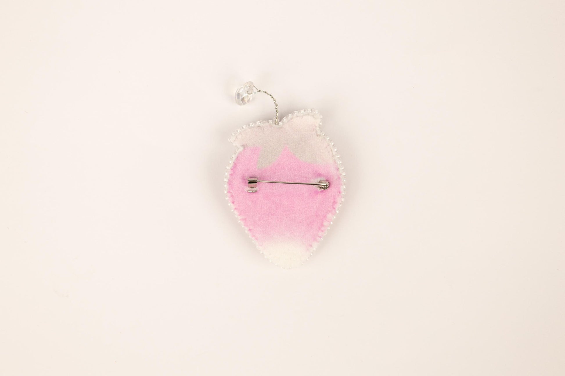 a pink and white brooch hanging from a hook