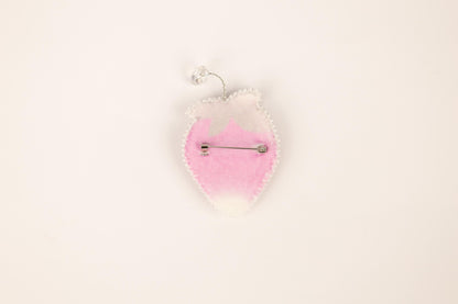a pink and white brooch hanging from a hook