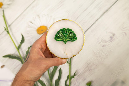 a hand holding a small green leaf on a white surface