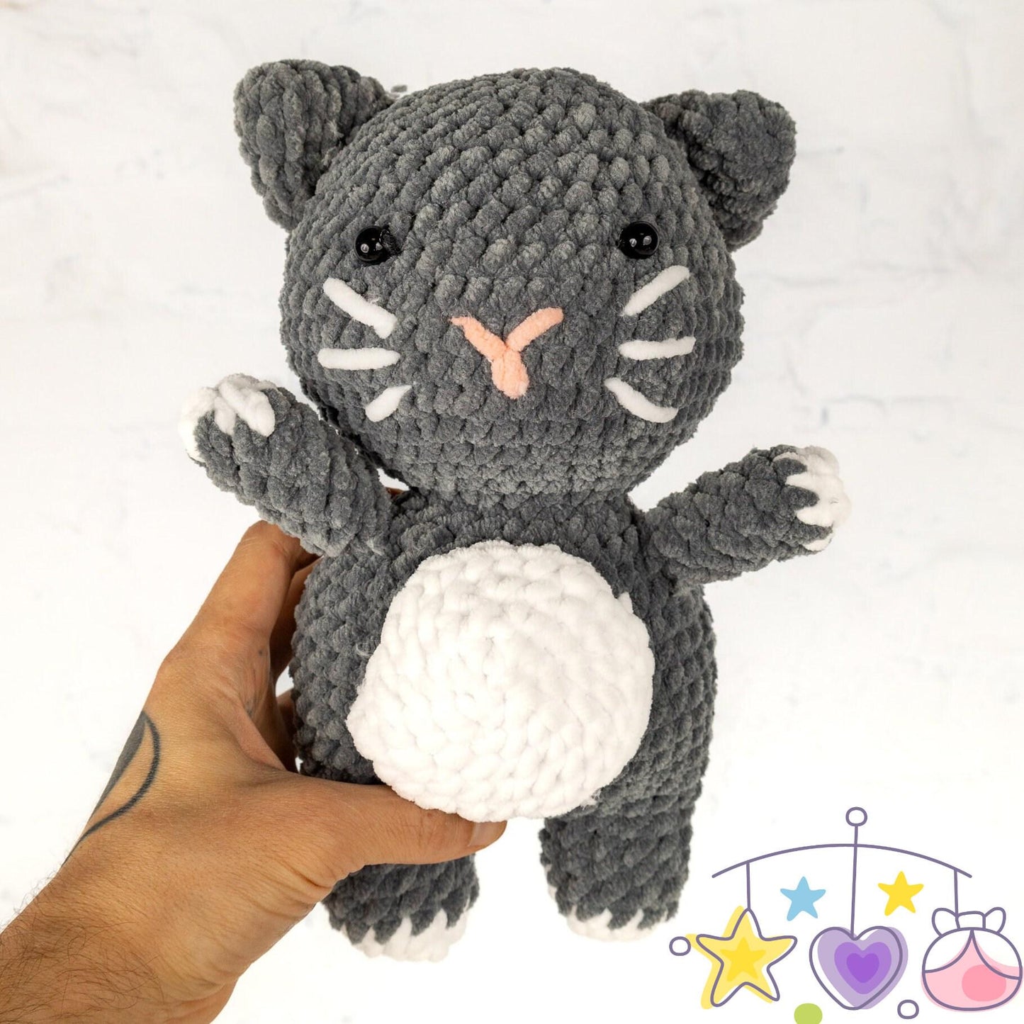 a crocheted black and white cat next to a ball of yarn