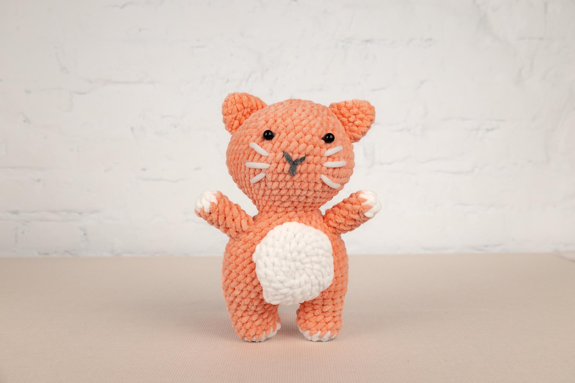 a crocheted orange cat standing on its hind legs