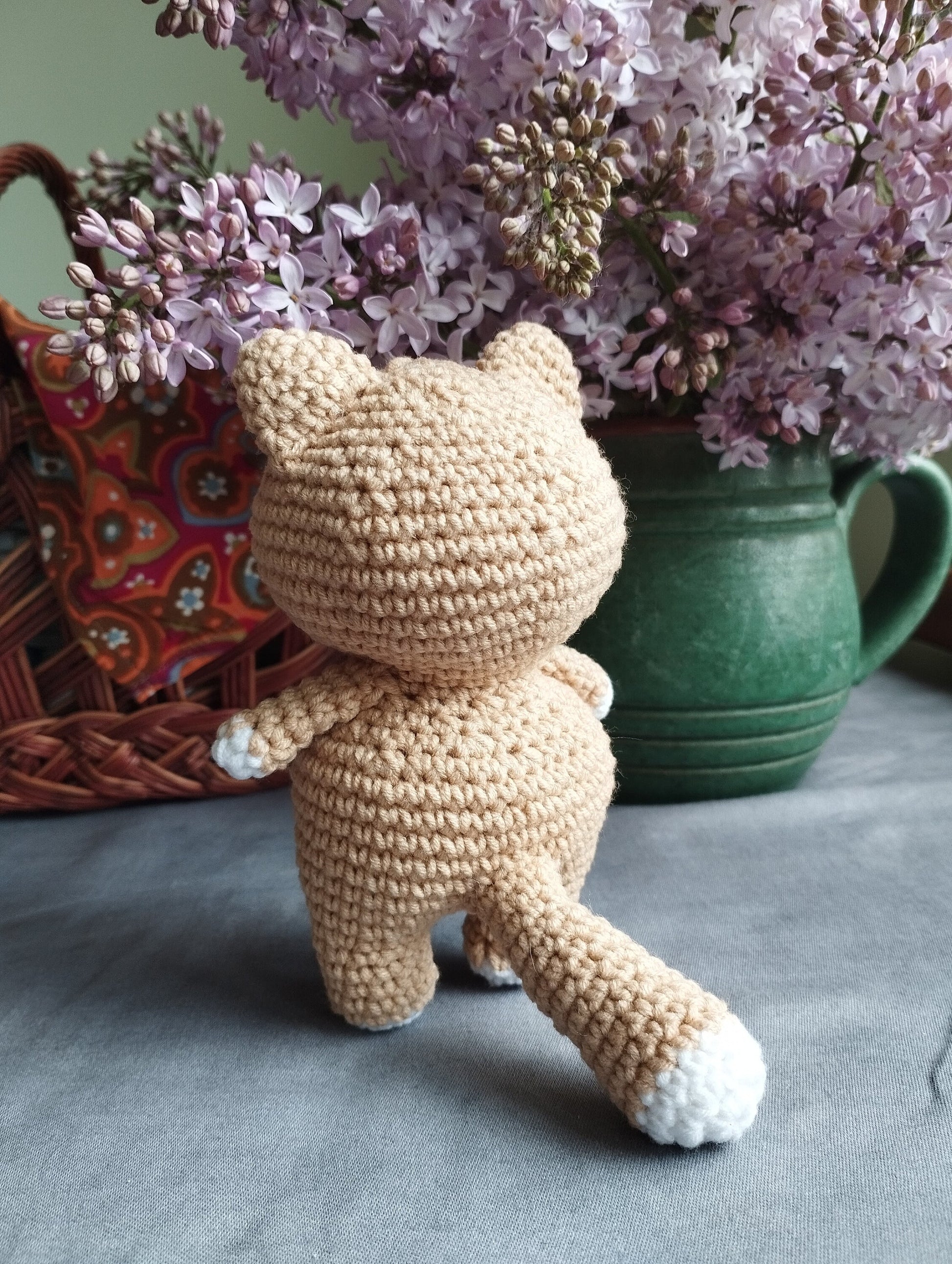 a crocheted teddy bear sitting next to a vase of flowers
