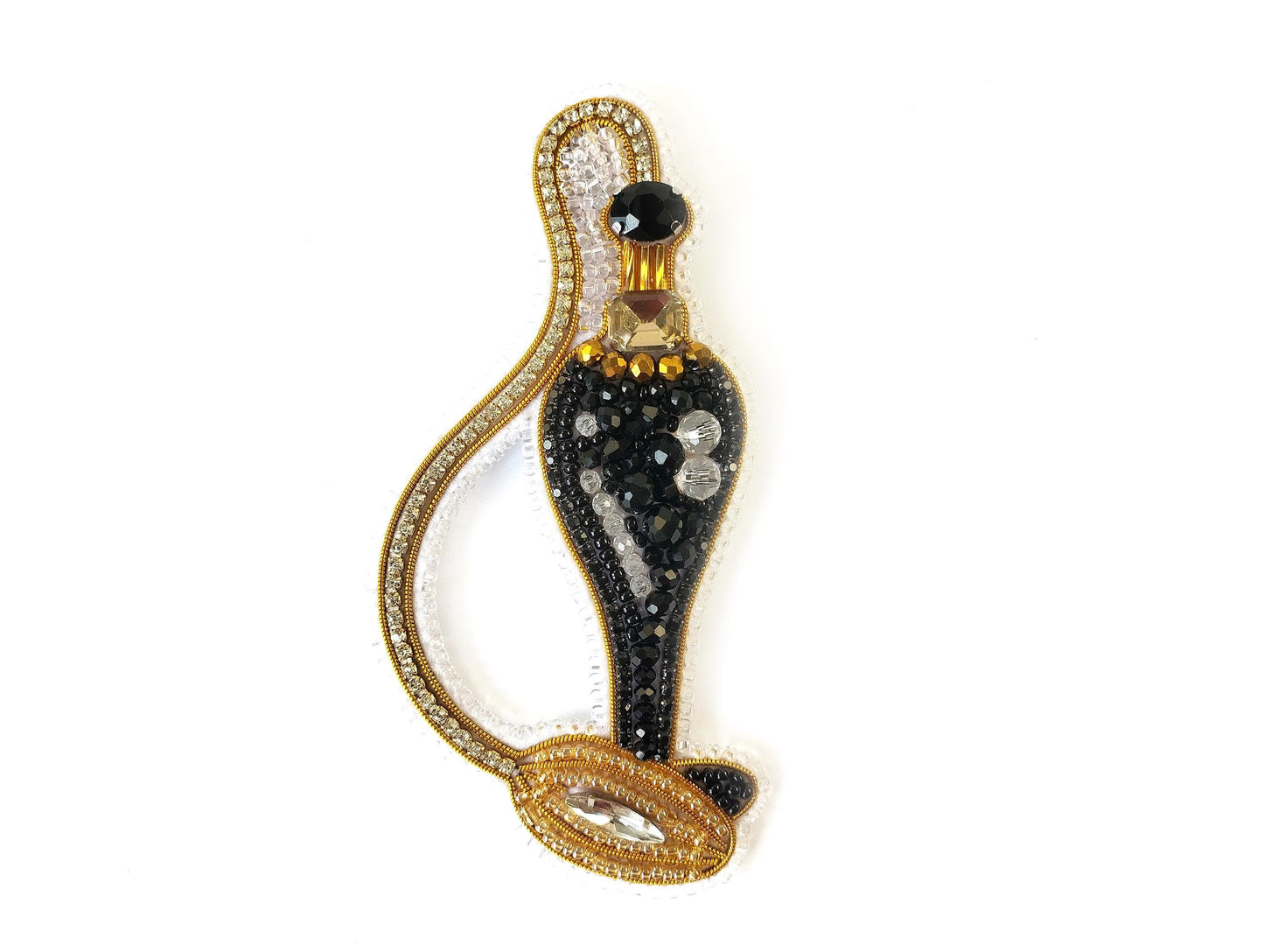 A decorative black perfume bottle with gold accents and sparkling rhinestones.