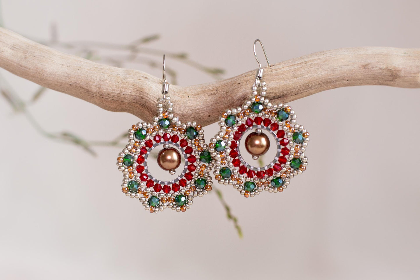 a pair of red, green, and gold earrings on a branch