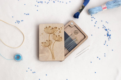 a wooden box with a needle and thread next to it