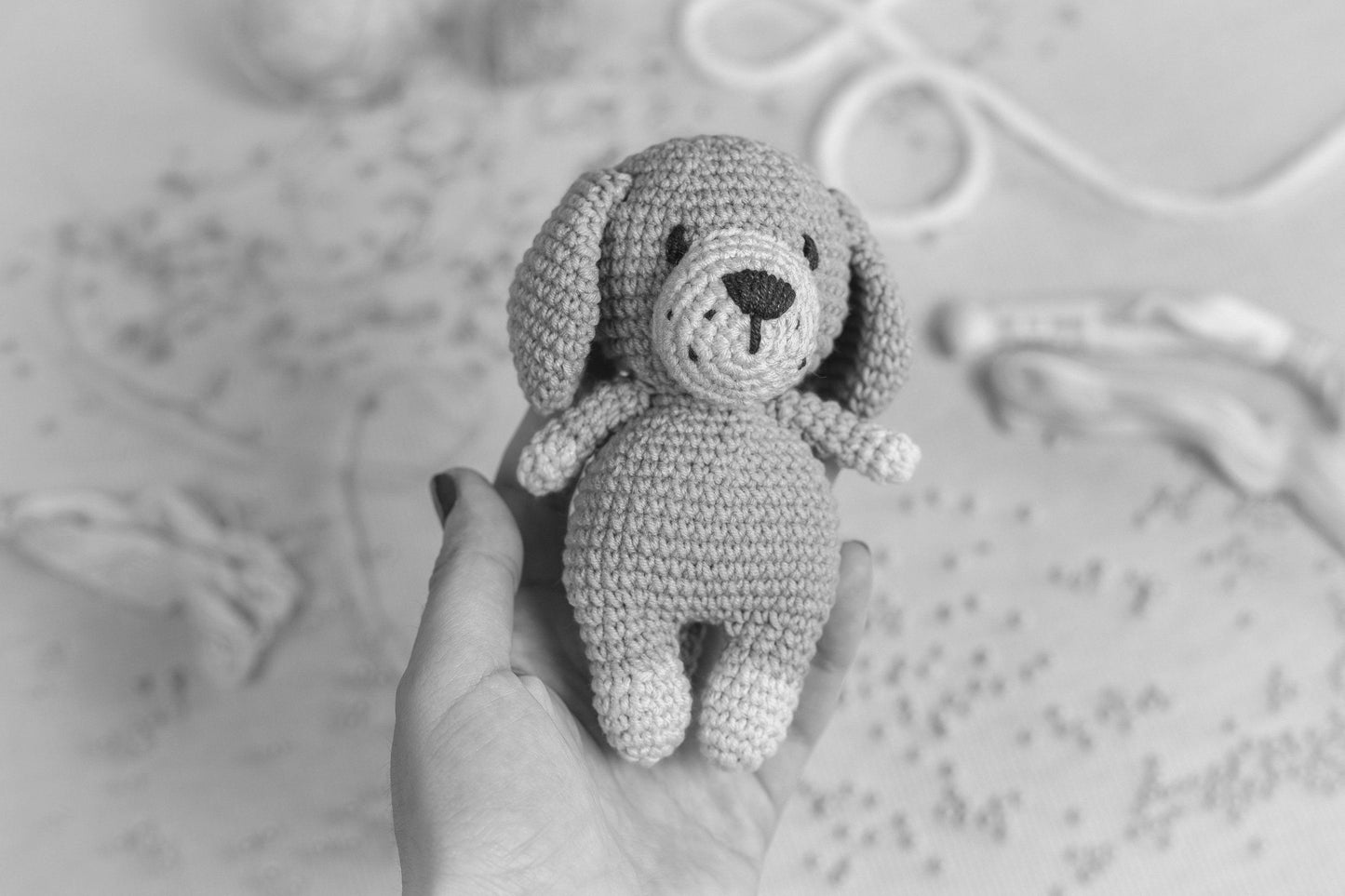 a hand holding a small crocheted dog