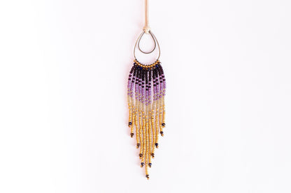 A beaded earring with a long, tassel-like fringe hanging from a hook against a white background.