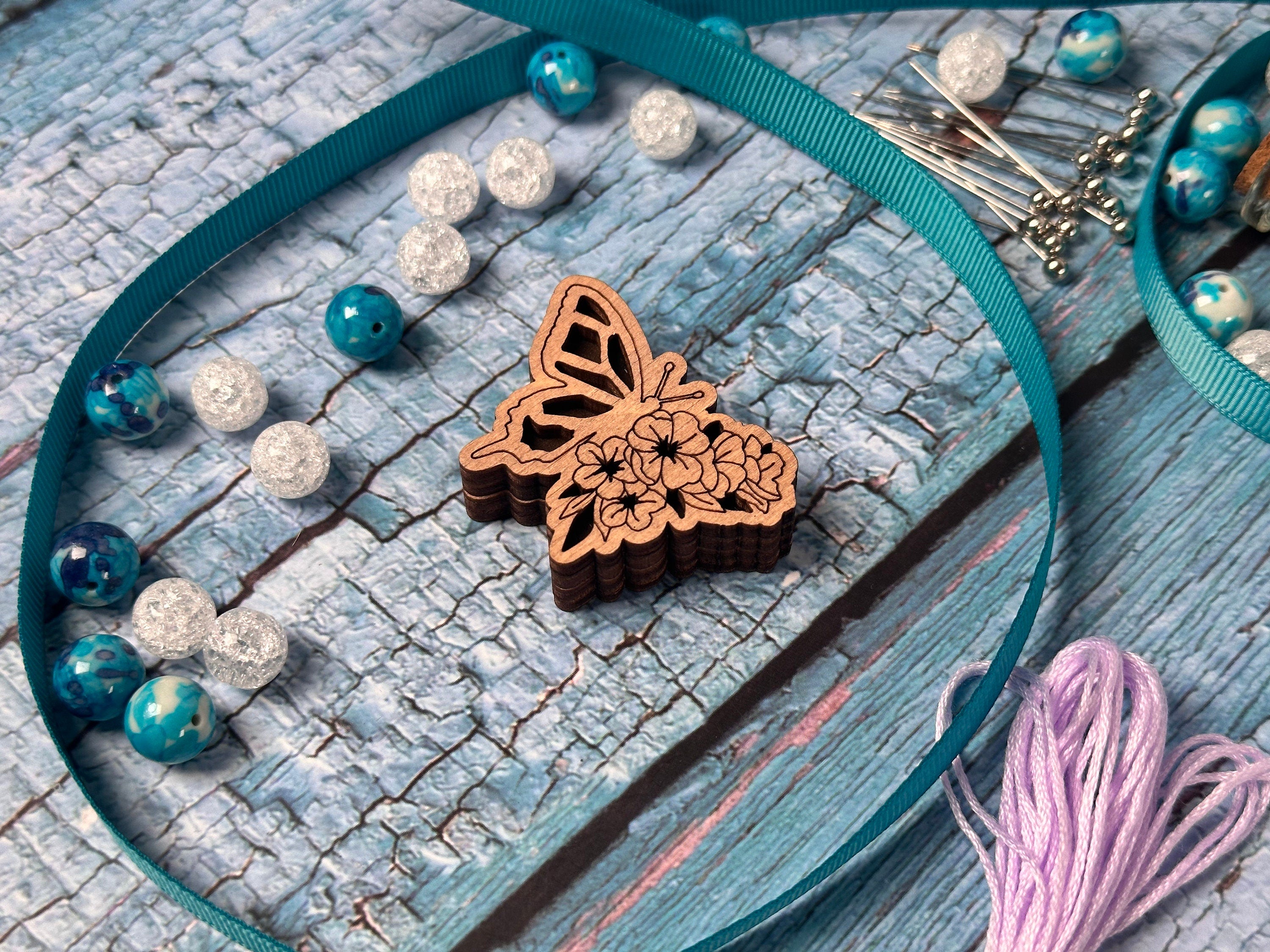 a wooden butterfly on a blue ribbon next to beads