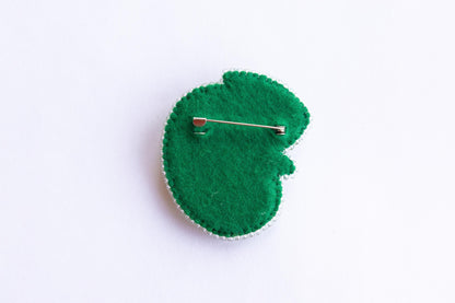 a green brooch with a pin on it