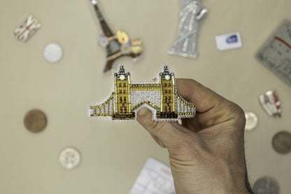 a person holding up a miniature model of a building