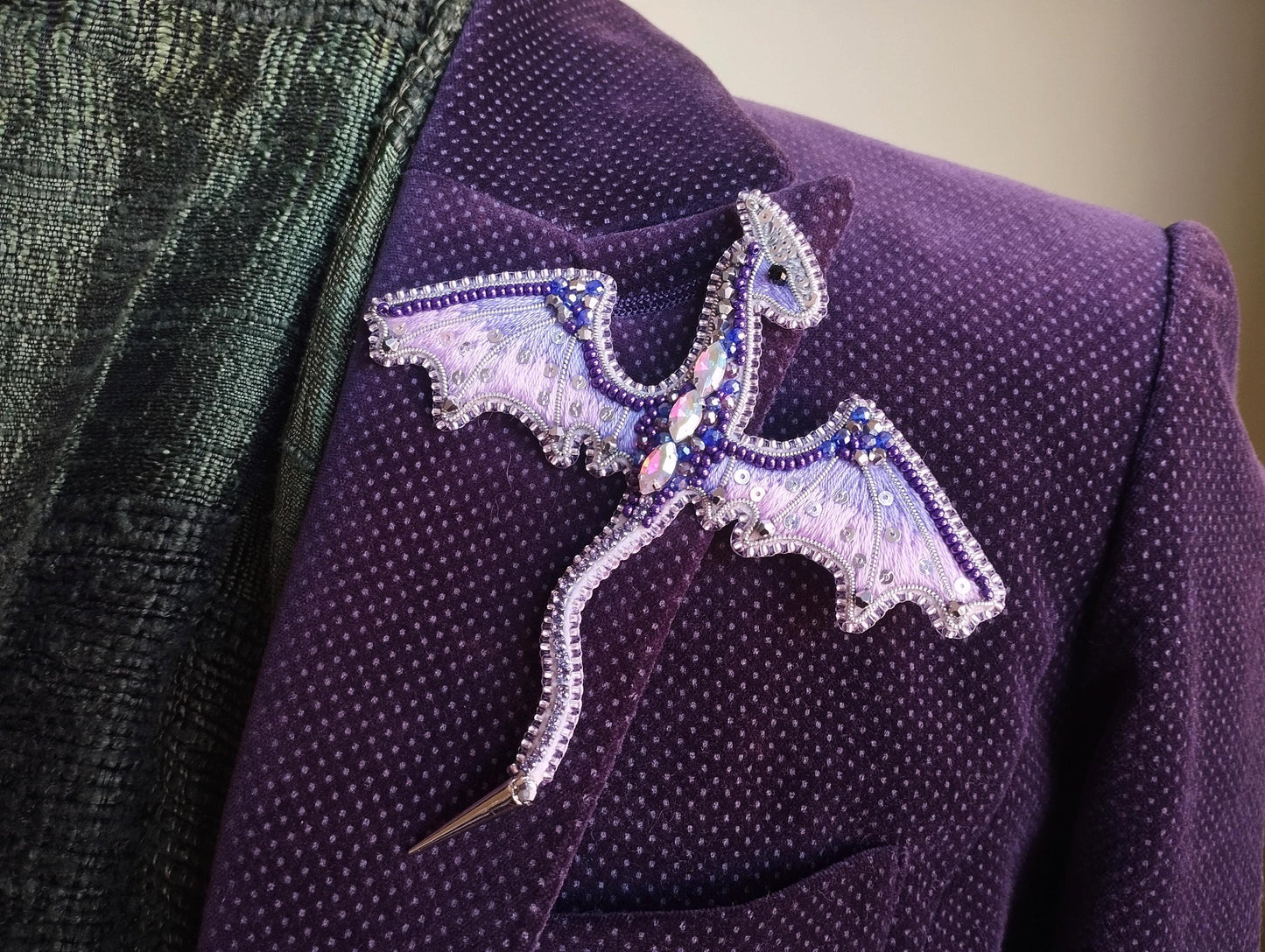 A purple jacket with a decorative dragon pin or brooch on the lapel.
